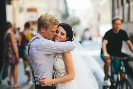 the bride and groom posing for the camera on the streets of the old townの写真素材