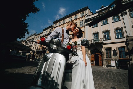 bride and groom posing on a vintage motor scooterの写真素材