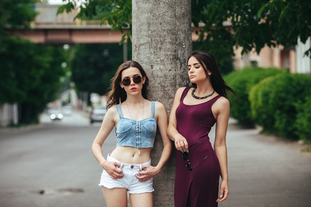 Two beautiful young girls posing on the background of the urban landscapeの写真素材