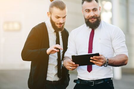 Two businessmen discussing something and looking at padの写真素材