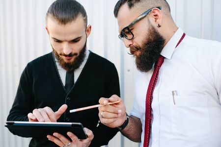 Two businessmen discussing something and looking at padの写真素材