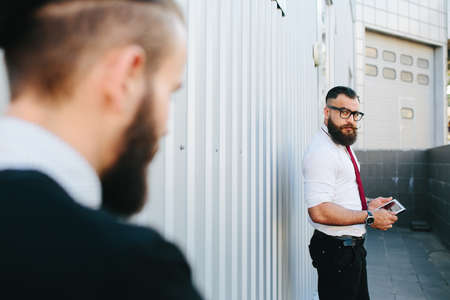 Two bearded businessman working on the streetの写真素材