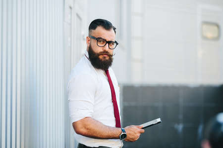 businessman stands with documents in hand against a white wallの写真素材