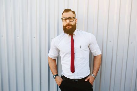 businessman stands with documents in hand against a white wallの写真素材
