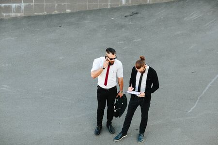 Two bearded businessman working on the street