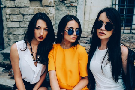Three young beautiful girls posing against the backdrop of an abandoned buildingの写真素材