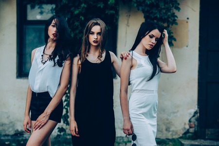 Two beautiful young girls in dresses posing in front of houseの写真素材