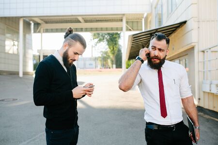Two bearded businessman working on the streetの写真素材