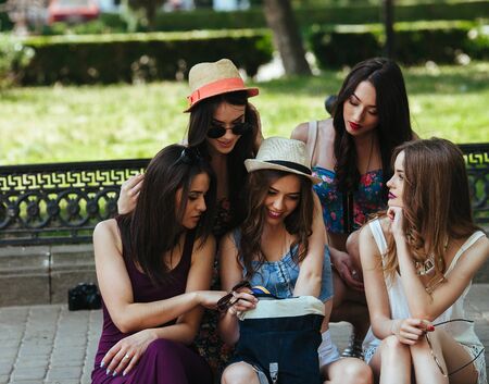 five beautiful young girls consider the bag in the parkの写真素材