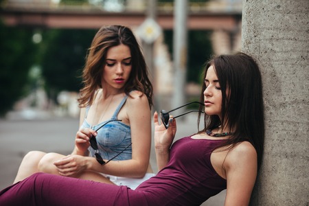 Two beautiful young girls posing on the background of the urban landscape