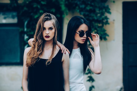 Two beautiful young girls in dresses posing in front of houseの写真素材