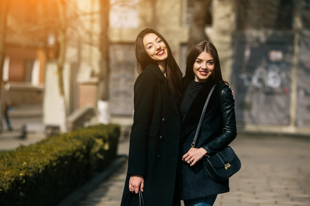 Two young adult women posing on a city streetの写真素材