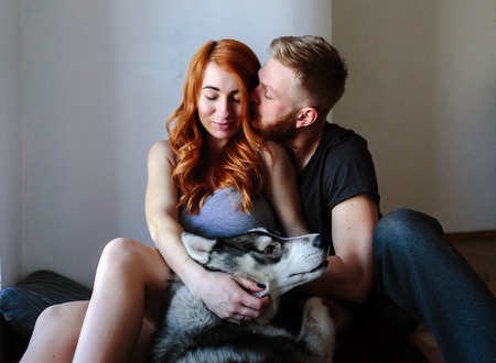 husband and pregnant wife relaxing together at home with a dog