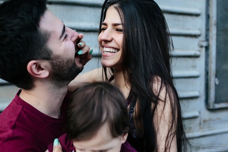 young beautiful family with child posing on the building backgroundの写真素材