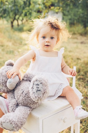little girl playing with a teddy bear in the gardenの写真素材