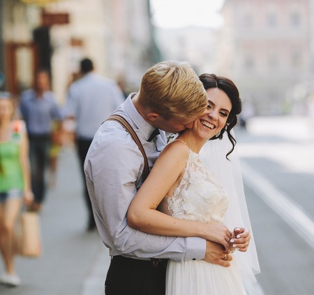 the bride and groom posing for the camera on the streets of the old townの写真素材