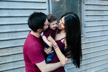 young beautiful family with child posing on the building backgroundの写真素材