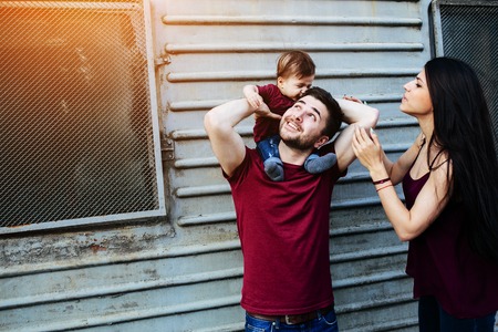 young beautiful family with child posing on the building backgroundの写真素材