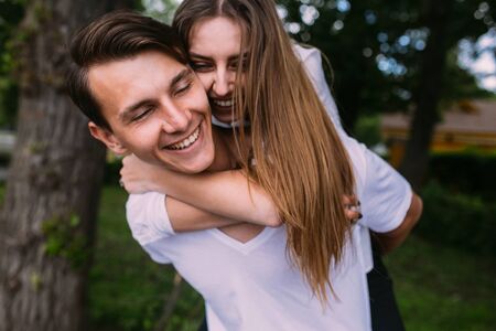 Young man carries his girlfriend on his back in the parkの写真素材