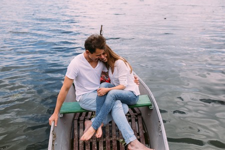 handsome guy and beautiful girl resting in a boat on the lakeの写真素材