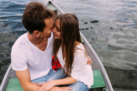 handsome guy and beautiful girl resting in a boat on the lakeの写真素材