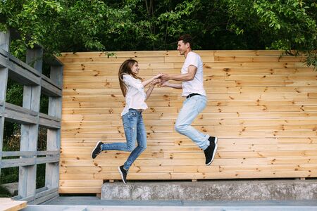 beautiful young couple posing on a background of a wooden wall at the cameraの写真素材