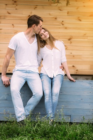 beautiful young couple posing on a background of a wooden wall at the cameraの写真素材