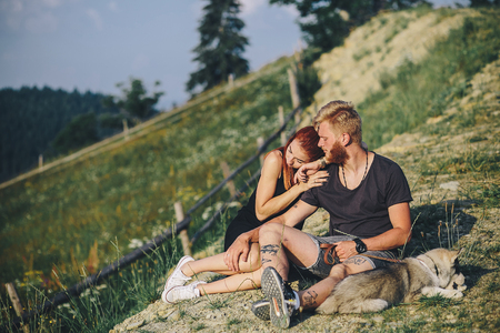 beautiful couple sits on a hill and hugging each otherの写真素材