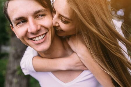 Young man carries his girlfriend on his back in the parkの写真素材