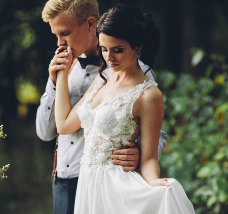 groom gently embracing his bride in the forestの写真素材