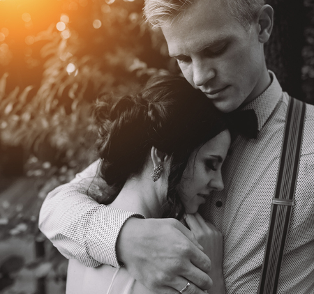groom gently embracing his bride in the forestの写真素材
