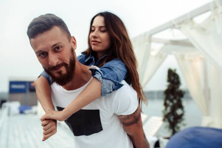 man carries girlfriend on his back and looking at the cameraの写真素材