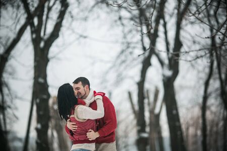 beautiful young couple posing in a snowy parkの写真素材