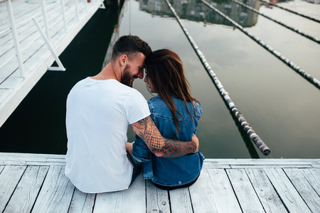 beautiful couple posing on a wooden pier at lakeの写真素材