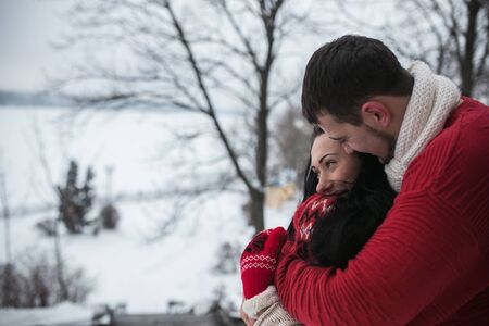 beautiful young couple posing in a snowy parkの写真素材