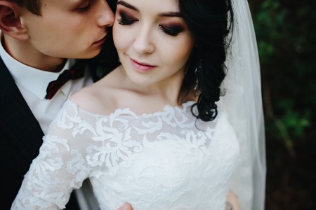 Bridal couple close to each other, posing in park