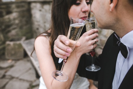 Beautiful wedding couple at a picnic under a tree drinking champagneの写真素材