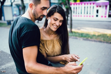 Couple watching something on a smart phone om the streetの写真素材