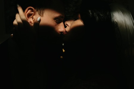 bride and groom in a dark room, illuminated by lightの写真素材