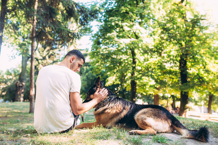 man and dog sitting on the grass in the park in the parkの写真素材