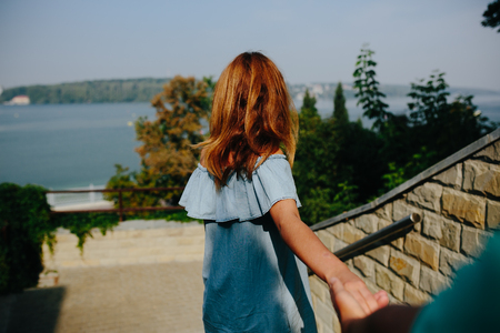 Young woman leading her lover by hand in parkの写真素材