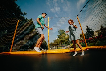 Full length of a happy couple jumping on trampoline in the parkの写真素材