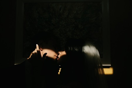 bride and groom in a dark room, illuminated by lightの写真素材
