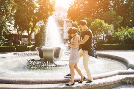 beautiful young couple at the fountain in the parkの写真素材