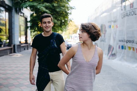 happy young couple of a handsome man and attractive woman walking on the street holding handsの写真素材