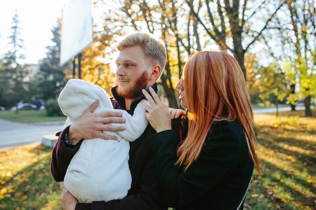 young family and newborn son posing for the camera in autumn parkの写真素材