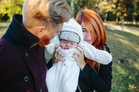 young family and newborn son posing for the camera in autumn parkの写真素材