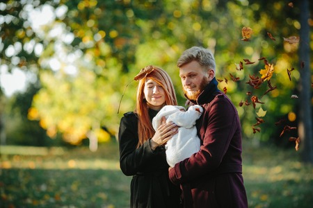 young family and newborn son posing for the camera in autumn parkの写真素材