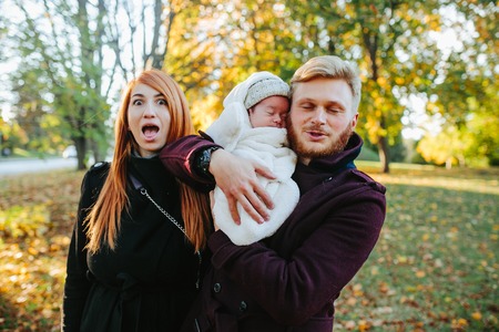 young family and newborn son posing for the camera in autumn parkの写真素材