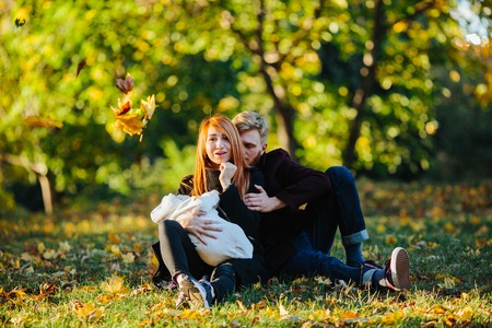 young family and newborn son posing for the camera in autumn parkの写真素材